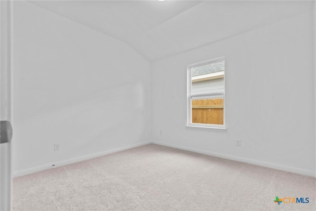 carpeted empty room featuring vaulted ceiling