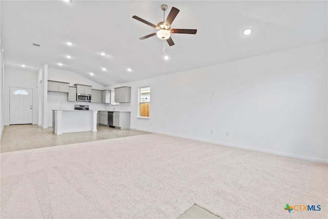 unfurnished living room featuring ceiling fan, light carpet, and vaulted ceiling