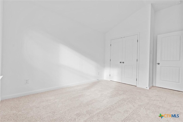 empty room with light colored carpet and lofted ceiling