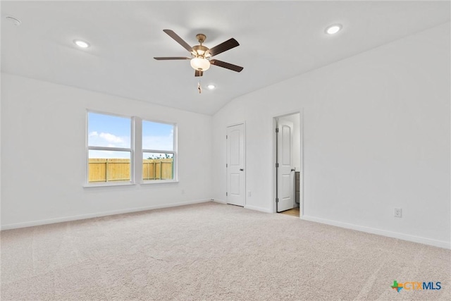 carpeted spare room with ceiling fan and vaulted ceiling