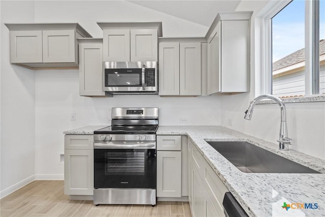 kitchen with gray cabinets, light stone countertops, sink, and stainless steel appliances