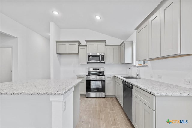 kitchen featuring gray cabinetry, light stone countertops, sink, a center island, and appliances with stainless steel finishes