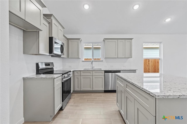 kitchen featuring gray cabinets, sink, light stone countertops, and stainless steel appliances