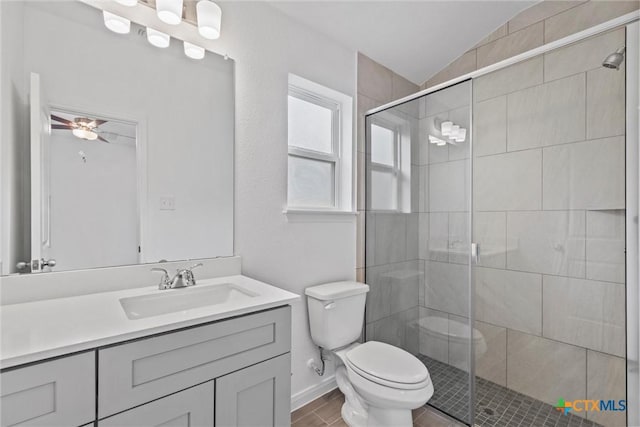 bathroom featuring vanity, vaulted ceiling, a shower with door, ceiling fan, and toilet