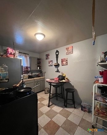 kitchen with a kitchen breakfast bar, gray cabinets, and stainless steel refrigerator