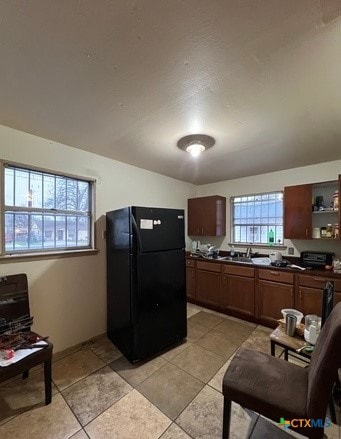 kitchen with black fridge, sink, and light tile patterned flooring