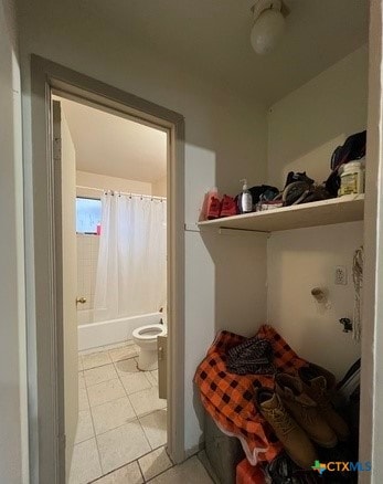 bathroom featuring toilet, shower / tub combo with curtain, and tile patterned flooring