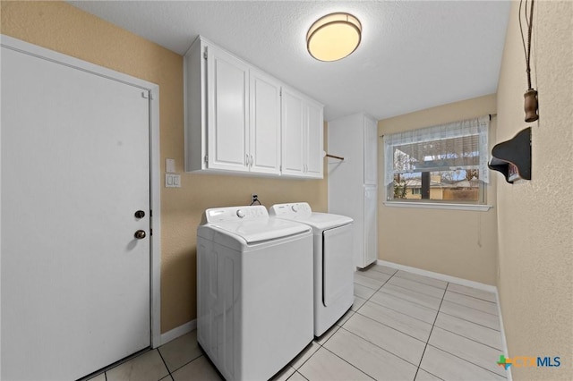 laundry room with light tile patterned flooring, cabinets, washer and clothes dryer, and a textured ceiling