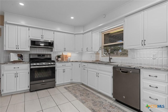 kitchen with white cabinetry, sink, decorative backsplash, light stone counters, and stainless steel appliances