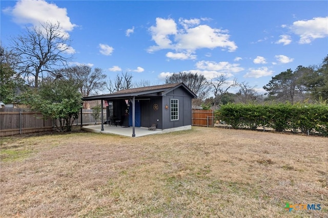 rear view of house with an outdoor structure, a patio area, and a lawn