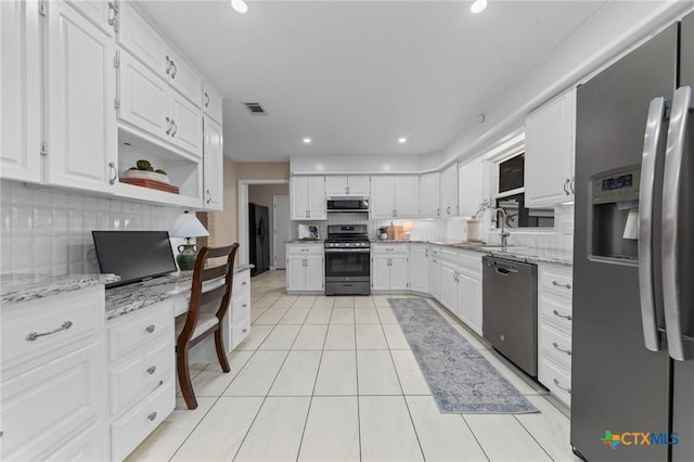 kitchen with sink, light stone counters, black appliances, decorative backsplash, and white cabinets