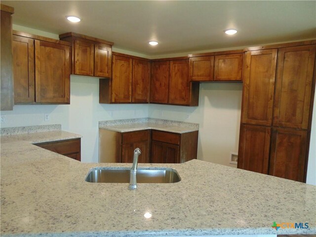 3204 Salt Fork Dr, Killeen, TX 76549 - kitchen with a sink, brown cabinetry, light stone countertops, and recessed lighting