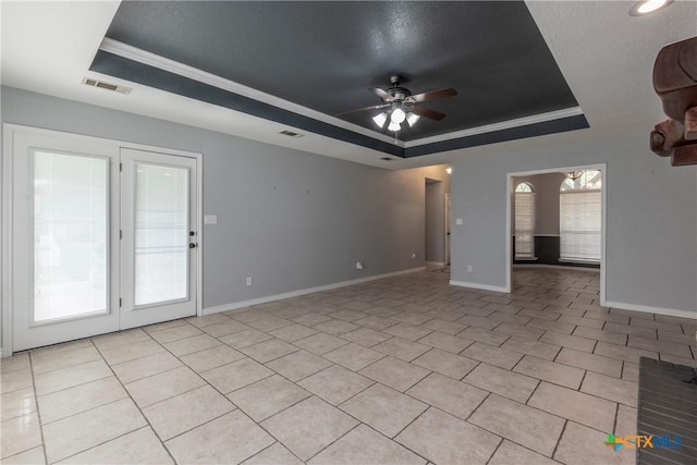 unfurnished living room featuring a raised ceiling, ceiling fan, and plenty of natural light