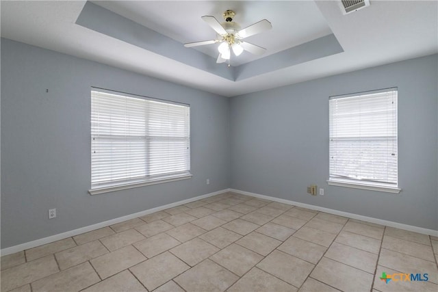 unfurnished room featuring a tray ceiling, ceiling fan, and light tile patterned floors