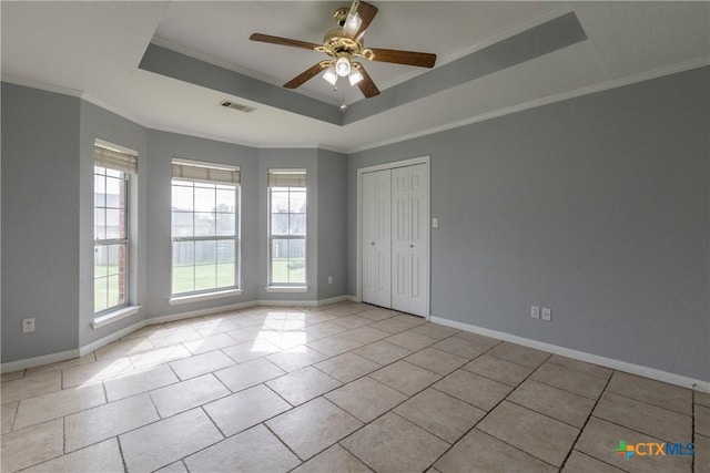 tiled spare room featuring a tray ceiling, ceiling fan, and ornamental molding