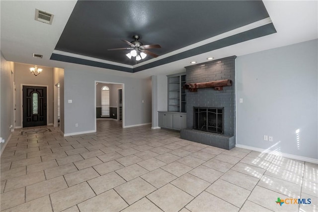 unfurnished living room featuring light tile patterned floors, ceiling fan with notable chandelier, a raised ceiling, and a brick fireplace