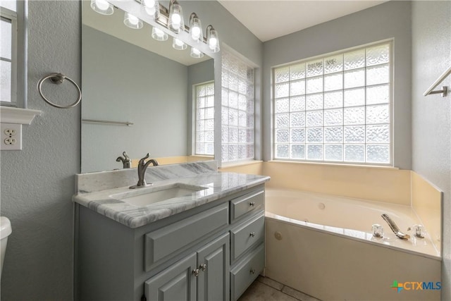 bathroom featuring tile patterned flooring, vanity, a bathtub, and toilet