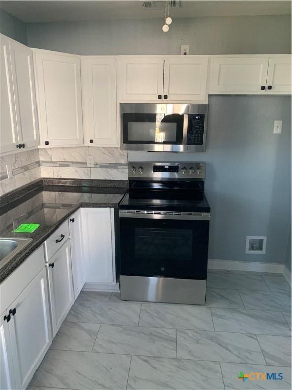 kitchen with white cabinets, backsplash, and stainless steel appliances