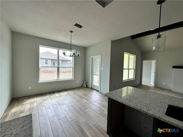 2571 Cedar Glen Dr, Belton, TX 76513 - kitchen featuring a chandelier, light wood-style floors, light stone countertops, hanging light fixtures, and a textured ceiling