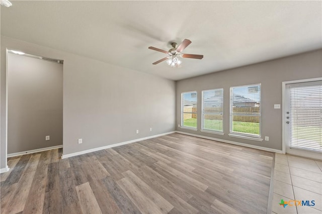 spare room featuring baseboards, ceiling fan, and light wood finished floors