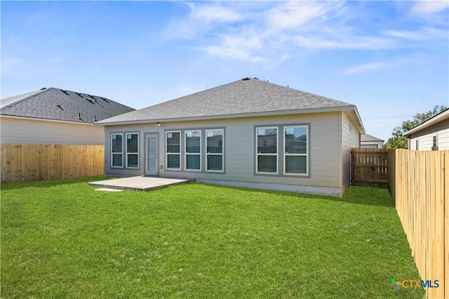 back of house with a shingled roof, a fenced backyard, and a yard