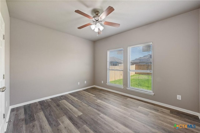 spare room featuring a ceiling fan, baseboards, and wood finished floors