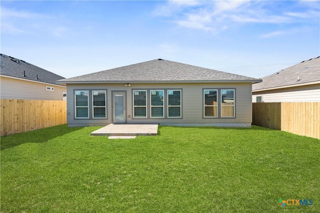 rear view of house featuring a yard, a shingled roof, and a fenced backyard