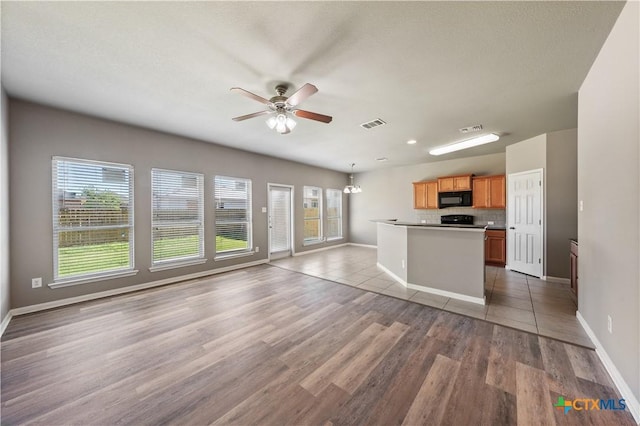 kitchen featuring light wood-style floors, black microwave, a healthy amount of sunlight, and open floor plan