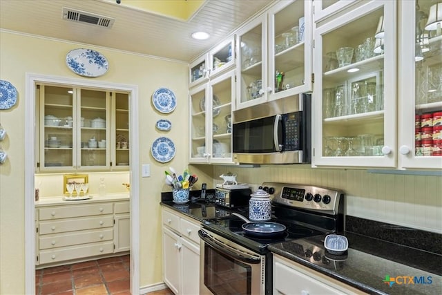 13650 Blackberry Rd, Salado, TX 76571 - kitchen with stainless steel appliances, glass insert cabinets, crown molding, dark tile patterned flooring, and white cabinets