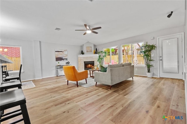 living room with baseboards, visible vents, ceiling fan, a fireplace, and light wood-type flooring