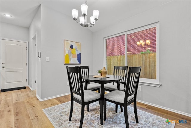 dining space featuring baseboards, light wood finished floors, and an inviting chandelier