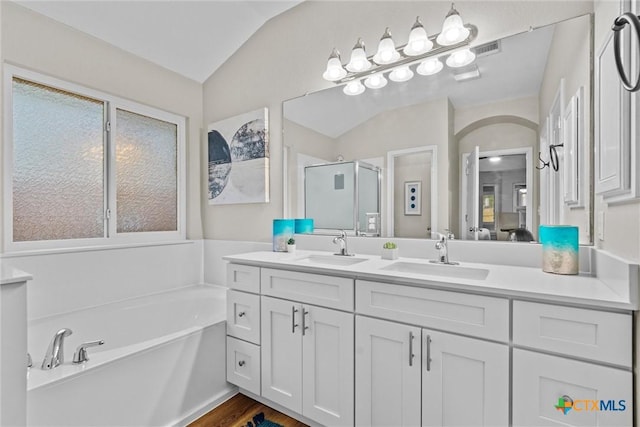 full bathroom with a stall shower, a bath, a sink, and vaulted ceiling