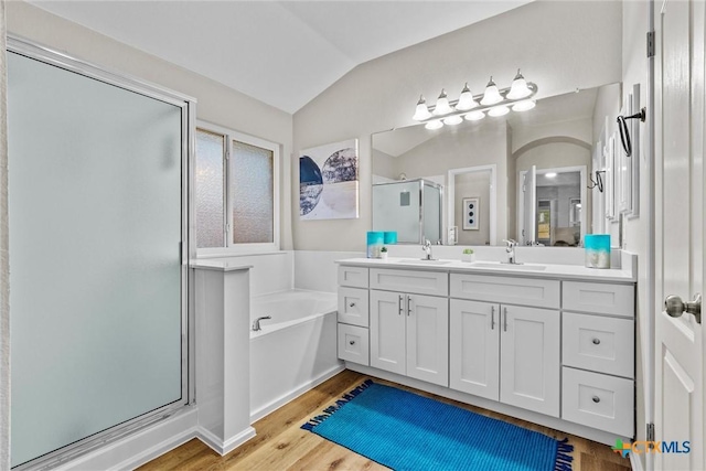full bathroom with lofted ceiling, wood finished floors, vanity, a stall shower, and a bath