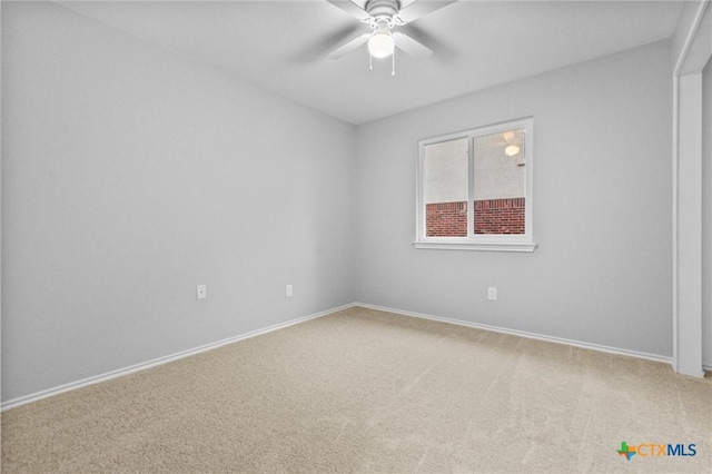 carpeted spare room featuring baseboards and a ceiling fan