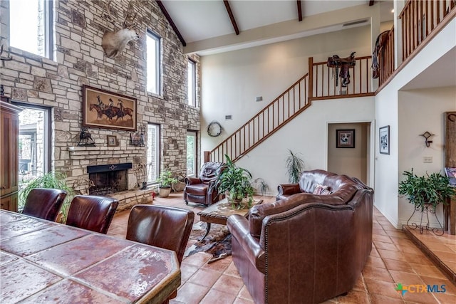 10767 Rosemar Ln, Adkins, TX 78101 - living area with high vaulted ceiling, light tile patterned floors, stairway, a stone fireplace, and beam ceiling