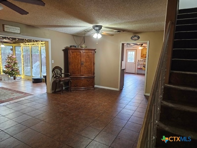 spare room with ceiling fan, a textured ceiling, and dark tile patterned floors