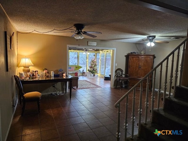 interior space featuring ceiling fan, dark tile patterned flooring, and a textured ceiling