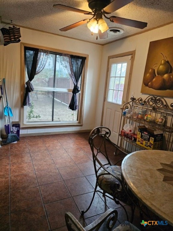 dining area featuring ceiling fan, ornamental molding, tile patterned floors, and a textured ceiling