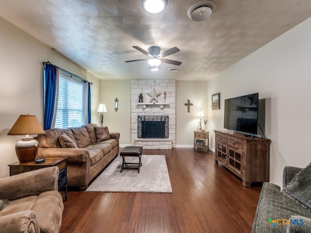 living room featuring ceiling fan, dark wood-type flooring, a fireplace, and baseboards