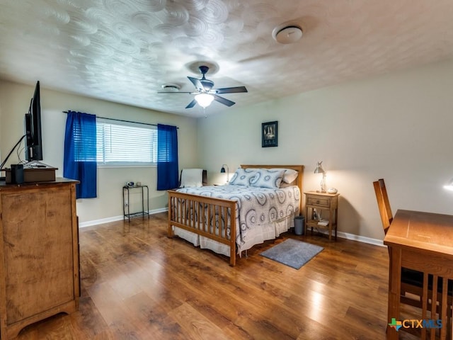 bedroom featuring baseboards, wood finished floors, and a ceiling fan