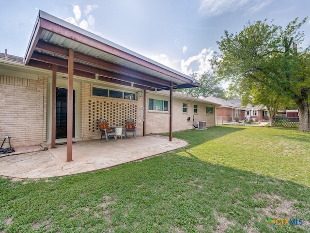 back of property with central AC, brick siding, and a patio