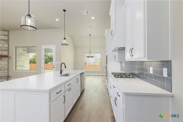 kitchen with a center island with sink, hanging light fixtures, sink, white cabinetry, and appliances with stainless steel finishes