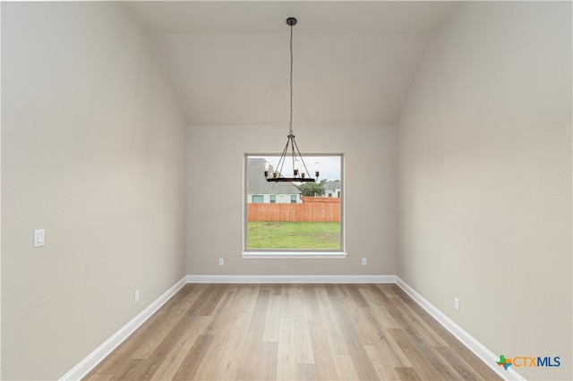 unfurnished dining area featuring hardwood / wood-style floors, lofted ceiling, and a notable chandelier