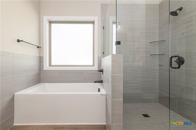 bathroom with independent shower and bath and tile walls