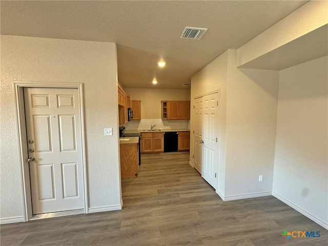 kitchen featuring black appliances, sink, wood-type flooring, and a textured ceiling