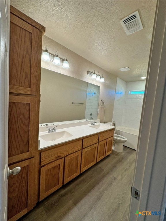 full bathroom with vanity, wood-type flooring, a textured ceiling, and toilet