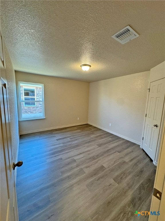 spare room featuring wood-type flooring and a textured ceiling