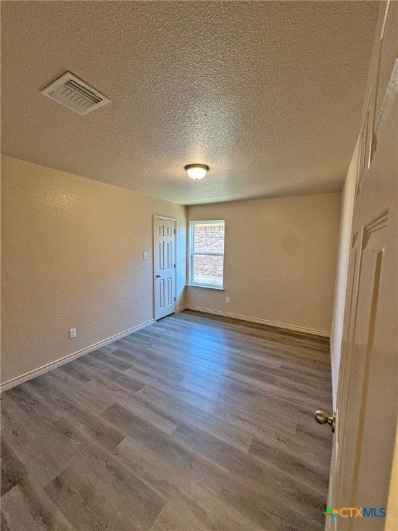 unfurnished room featuring hardwood / wood-style flooring and a textured ceiling