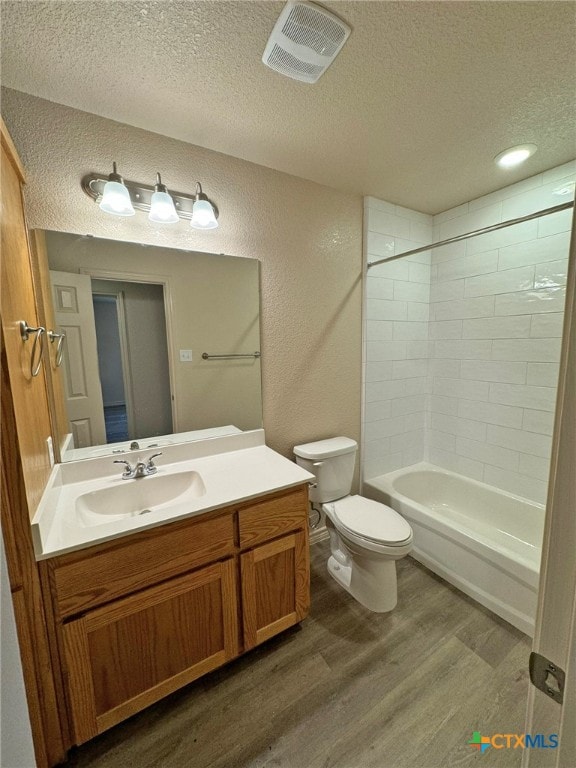 full bathroom featuring vanity, tiled shower / bath combo, toilet, a textured ceiling, and wood-type flooring