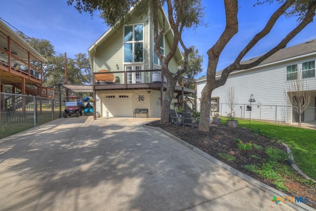 rear view of house with concrete driveway, fence, and a garage